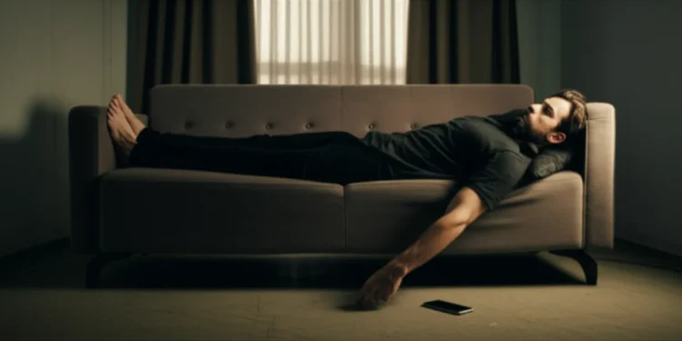 Man lying on couch staring at ceiling in dim apartment